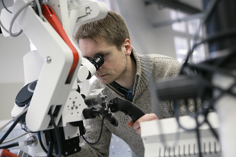 Forschung/Technik/Mann schaut durch Mikroskop