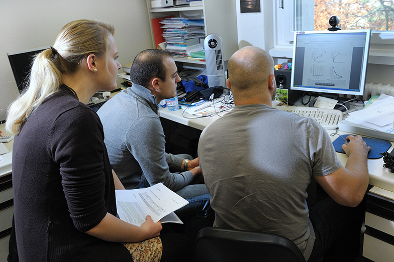 Forschung/Technik/Büro/Team wertet Daten an Bildschirm aus