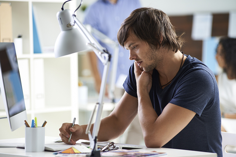 Arbeitsplatz/Büro/junger Mann an Schreibtisch/Telefoniert/schreibt