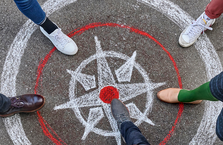 Auf Boden gezeichneter Kompass und Füsse, die darauf stehen