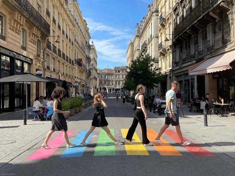 Studierende gehen über regenbogenfarbenen Zebrastreifen, Symbolbild für Mobilität für Studierende