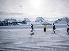 Eine kleine Gruppe von Menschen ist am Langlaufski fahren mit schöner Sicht auf Berge.