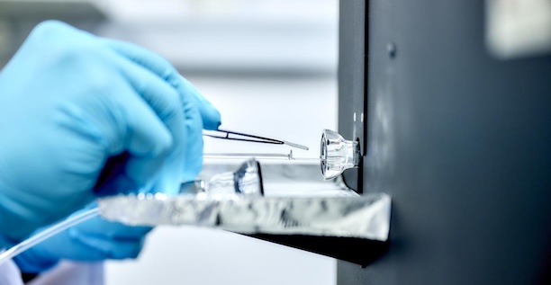 Hände in Handschuhen mit Pinzette