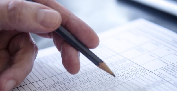 Hand mit Bleistift füllt Formular aus